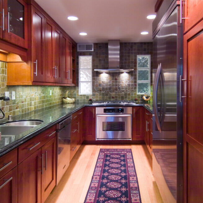 A kitchen with wooden cabinets and tile walls.